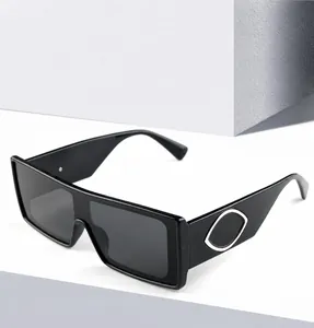 Detail of black rectangular sunglasses featuring a golden eye-shaped metal temple decor