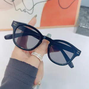 Classic black square retro sunglasses with tinted lenses held in hand against white background