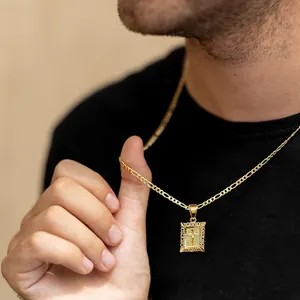 Nahaufnahme einer vergoldeten Figaro-Kette mit texturiertem Kreuzanhänger an einem Model