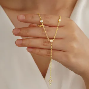 Close-up of golden Y-shaped necklace featuring bezel-set crystals and a cross pendant