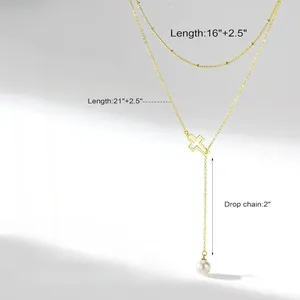 Detail view of gold layered cross necklace showing chain lengths and white pearl charm