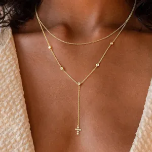 Close-up of gold Y-shaped necklace with cross pendant and zircons on model