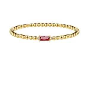 Bague élégante en perles dorées avec une pierre précieuse rouge sur fond blanc pur
