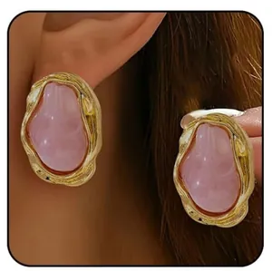 Dettaglio di orecchini barocchi placcati oro con pietre in resina rosa irregolari