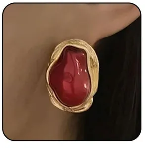 Dettaglio di un orecchino vintage in ottone dorato con una grande gemma cabochon rossa