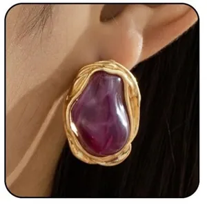 Orecchini barocchi in ottone dorato con perla viola indossati da una modella