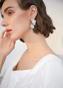 Macro shot of large silver layered flower earrings with textured metallic petals on model