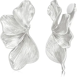 Detailed close-up of oversized silver floral earrings with radial texture and padded clip