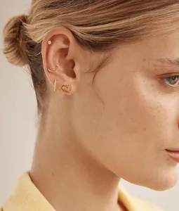 Gros plan de boucles d'oreilles papillon dorées minimalistes portées sur l'oreille de femme