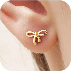 Gros plan de boucles d'oreilles nœud dorées minimalistes portées sur l'oreille féminine
