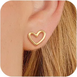 Vue macro de boucles d'oreilles cœur évidé minimalistes en or poli sur l'oreille