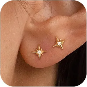 Gros plan de boucles d'oreilles Étoile du Nord dorées avec zircon sur l'oreille