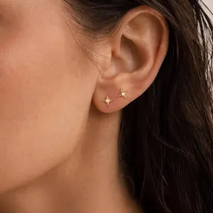 Détail de deux boucles d'oreilles étoile du nord dorées avec zircon sur l'oreille