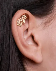 Macro view of gold lotus mandala cartilage clip earring on upper ear rim