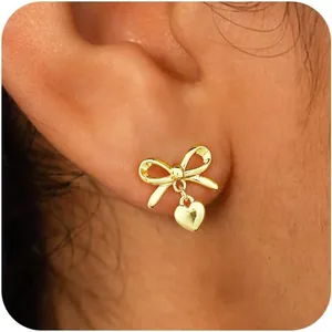 Elegantes pendientes de lazo dorado con pequeños corazones en la oreja de modelo