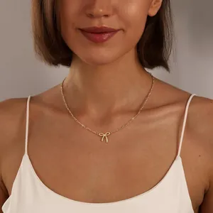 Dettaglio della collana con ciondolo a fiocco dorato su modella con catena Figaro lucida