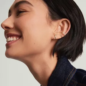 Ensemble de trois boucles d'oreilles papillon dorées avec pierres zircons sur un mannequin