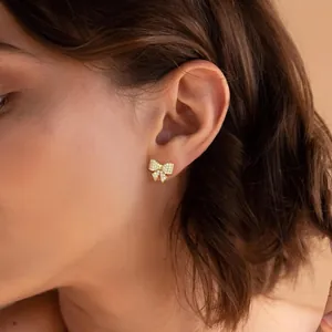 Primer plano de pendientes de lazo dorado con cristales en una modelo femenina