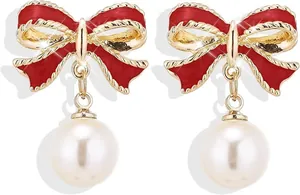 Detalle de pendientes de lazo rojo con perlas elegantes y bordes metálicos dorados