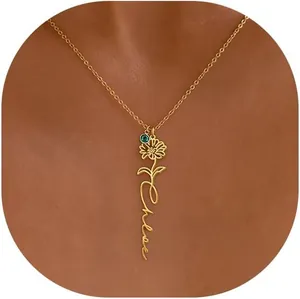 Close-up of personalized gold Chloe flower name necklace with green gemstone on model