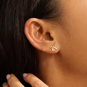 Primer plano de elegantes pendientes de lazo dorado con detalles calados en modelo