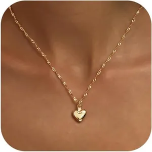 Dettaglio del ciondolo a cuore placcato oro su catena a corda indossato da una modella