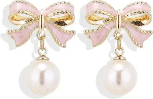 Detalle de pendientes de lazo rosa con bordes dorados y una gran perla blanca colgante