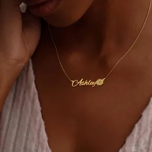 Close-up of golden personalized Ashley name necklace with daisy charm on a female model