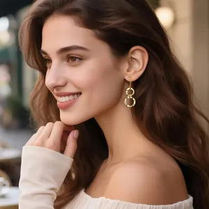 Gros plan de boucles d'oreilles bohèmes dorées entrelacées avec finition martelée sur modèle