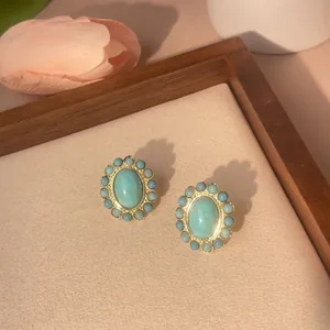Close-up of vintage gold plated brass studs featuring oval turquoise stones and bead trim