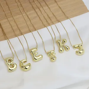 Detail of 3D gold bubble letter pendants with glossy finish and delicate chain