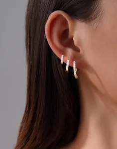 Close-up of gold plated brass huggie earrings set with clear cubic zirconia on ear
