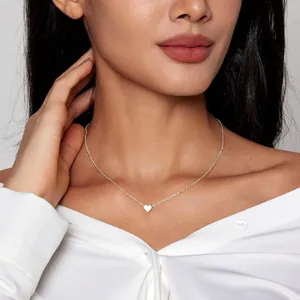 Primo piano di una collana con ciondolo a cuore minimalista con finitura argento lucido su modella