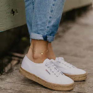 Cavigliera a doppio strato dorata con cuore abbinata a sneakers in tela con zeppa