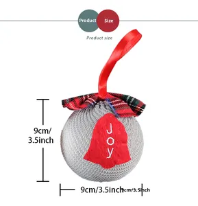 Detailed view showing 9cm grey knitted Christmas ball with JOY bell and red ribbon