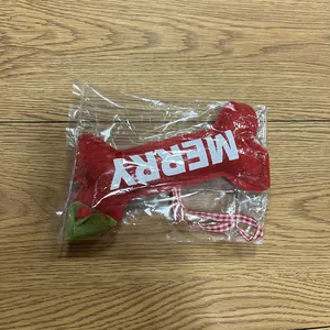 Detailed view of red plush bone ornament with Merry text in plastic packaging