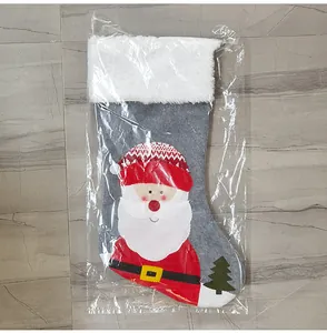 Detail view of gray felt Christmas stocking with plush cuff and Santa applique in packaging