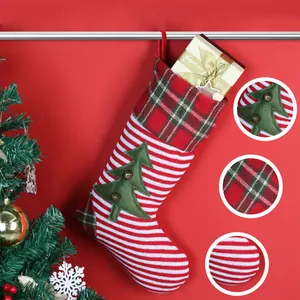 Gestrickter rot-weiß gestreifter Weihnachtsstrumpf mit Tannenbaum und Glockendeko