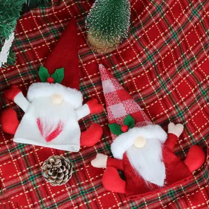 Two knit Christmas gnome wine bottle covers with red and white patterns and holly details