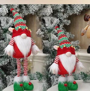 Close-up of festive Christmas gnomes with knit hats and striped legs on pine branches