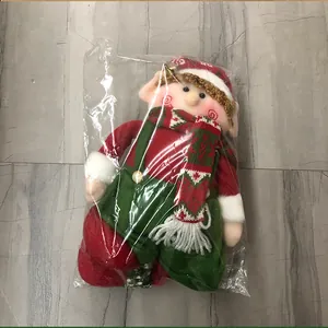 Detail of Christmas elf plush toy in red and green festive outfit with striped scarf