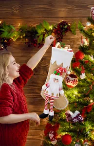 Close-up of a khaki knitted Christmas stocking with a plush elf character on a tree