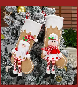 Detail of 3D Santa and girl figures on knitted khaki Christmas stockings hanging on a tree