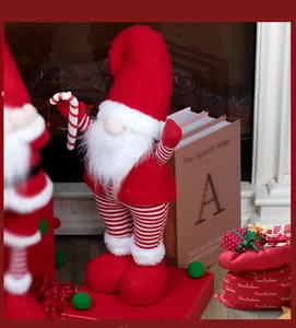 Close-up of a Nordic Christmas gnome with a long white beard holding a candy cane decor
