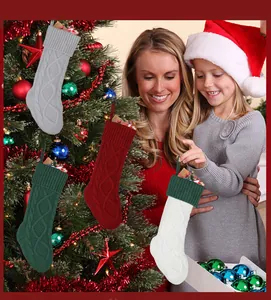 Detail van kabelgebreide kerstsokken in rood groen en grijs met ophanglussen