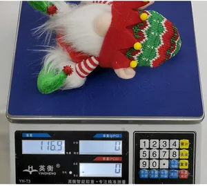 Detailed view of a Christmas gnome plush weighing 116.9g on a digital scale