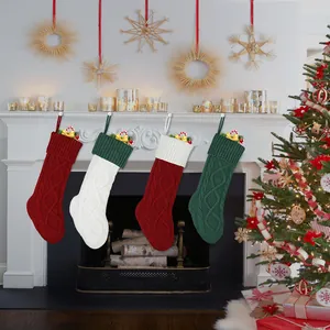 Set van 4 kabelgebreide kerstsokken in rood, groen en wit hangend aan de open haard