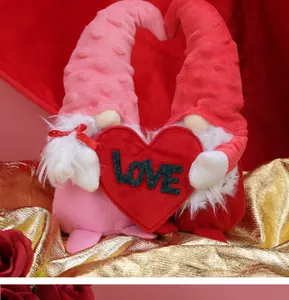 Close-up of plush Valentine gnomes set holding a red LOVE heart with a satin background