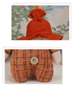 Close-up of handmade Thanksgiving scarecrow doll with orange felt hat and plaid fabric details