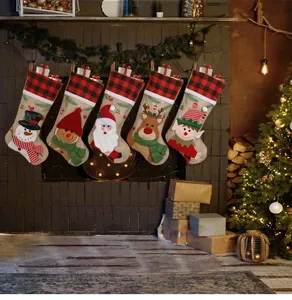 Close-up of burlap Christmas stockings with buffalo plaid and festive character embroidery